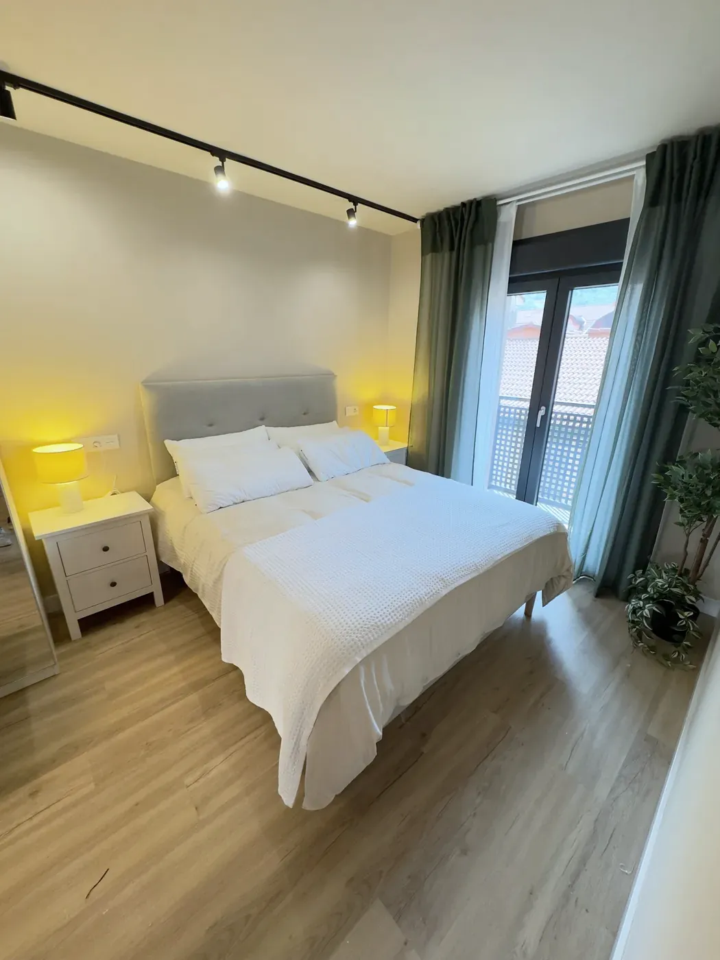 Suite bedroom with Queen Size bed, lamps on and green curtains